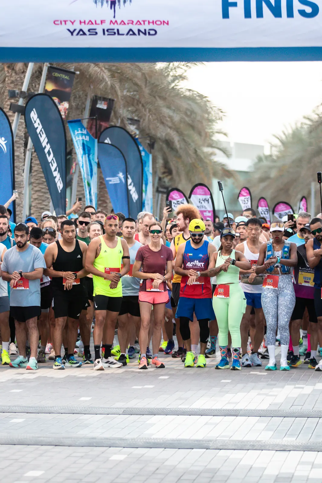 Runners gather at the start line of the City Half Marathon on Yas Island, wearing colorful athletic gear and race bibs.