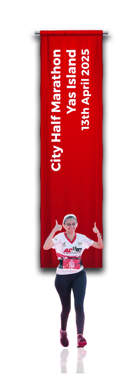 A runner celebrates while crossing the finish line under a red banner displaying City Half Marathon, Yas Island, 13th April 2025.