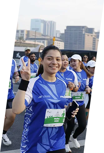 A group of enthusiastic runners in blue jerseys participate in a fun run, showcasing a lively urban backdrop.