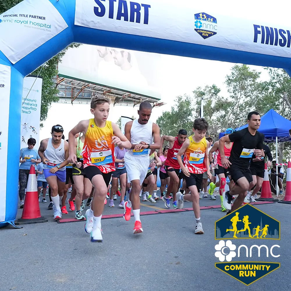 Runners take off from the start line at a community run event, with a vibrant atmosphere and various participants in athletic gear.