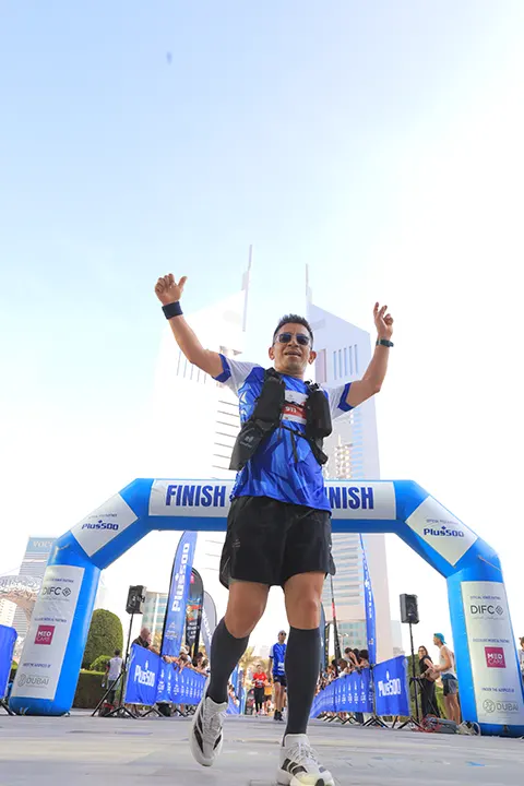 Participant celebrating after crossing the finish line at a city marathon during a community running event.