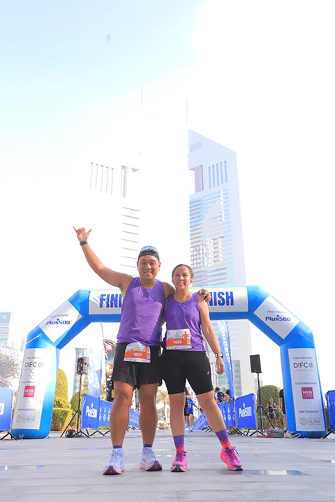 Two marathon participants celebrating together at the finish line after completing a community city marathon.