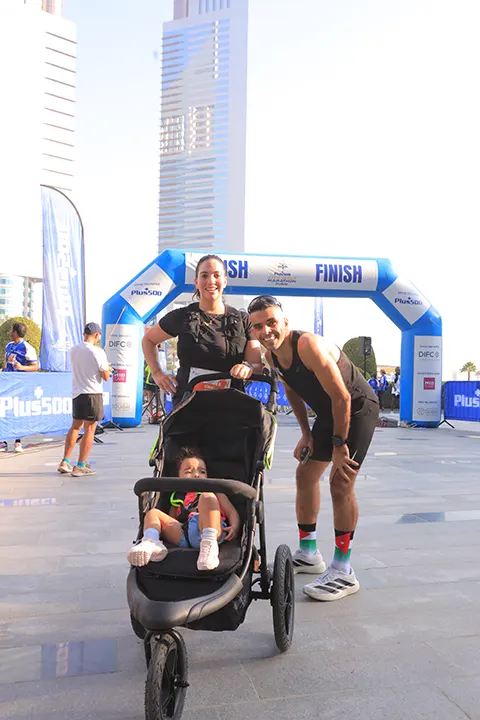 Family celebrating at the marathon finish line with their child after completing a community city running event.