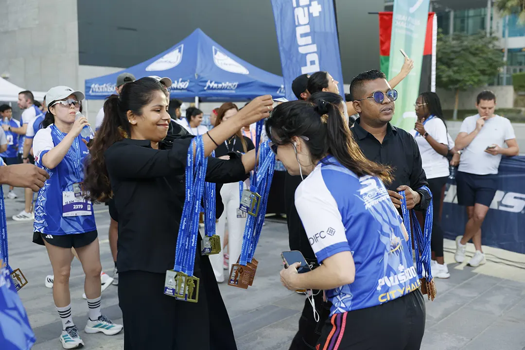 Volunteers presenting finisher medals to participants after completing a community city marathon and road race event.