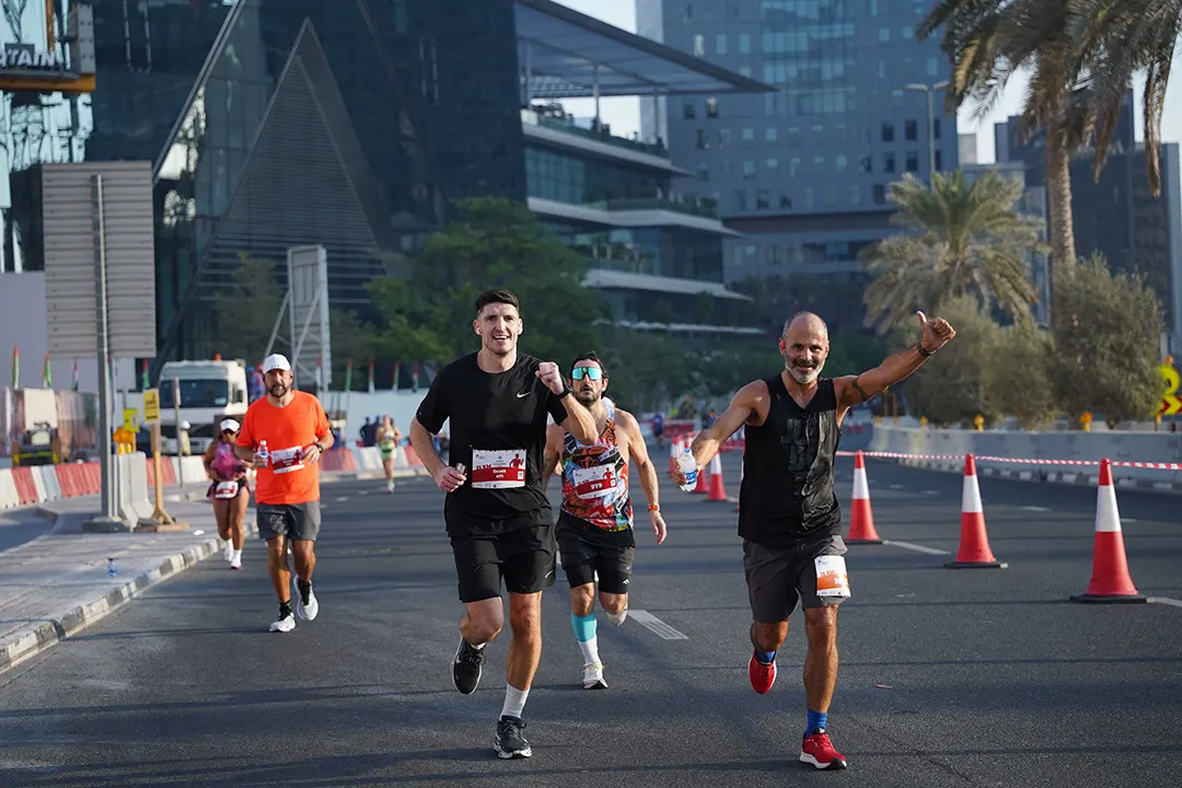Participants running in a city marathon during a community road race through a modern urban landscape.