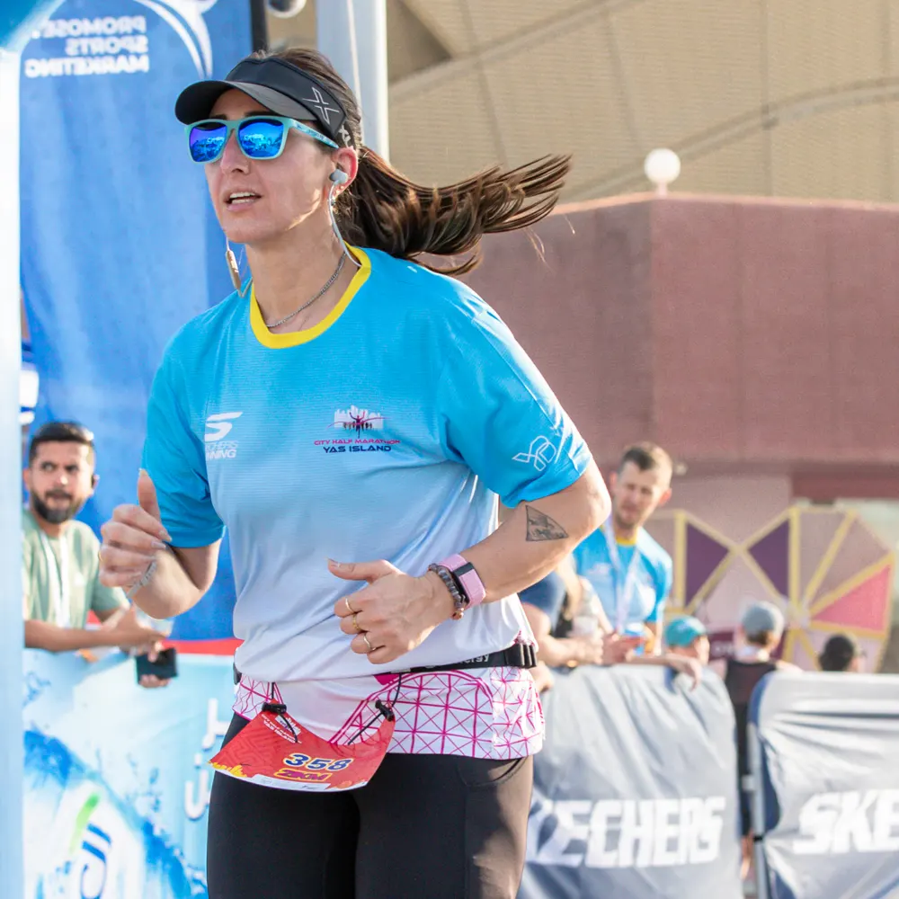 A person proudly holds up a gold medal with a colorful ribbon, celebrating a significant achievement in an outdoor setting.