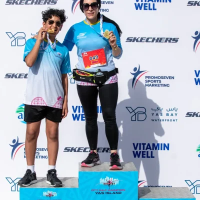 Two athletes celebrate their achievements on podiums at the City Half Marathon, displaying medals in front of a branded backdrop.