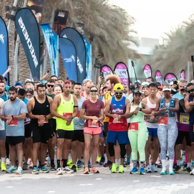 Runners gather at the start line of the City Half Marathon on Yas Island, wearing colorful athletic gear and race bibs.